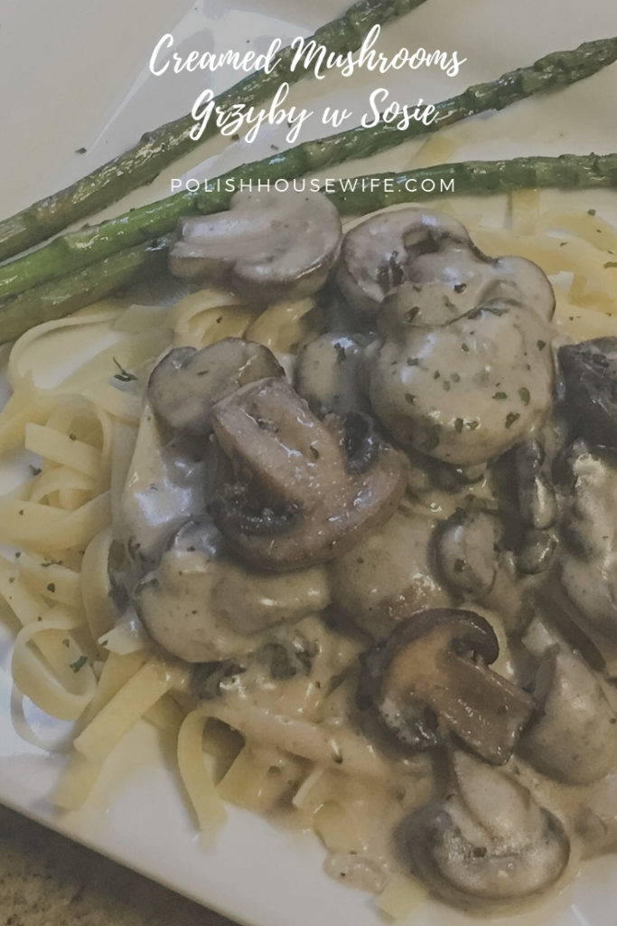 mushrooms in cream sauce over pasta with asparagus on white plate