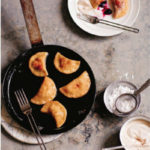 pierogi in a skillet with some on a plate