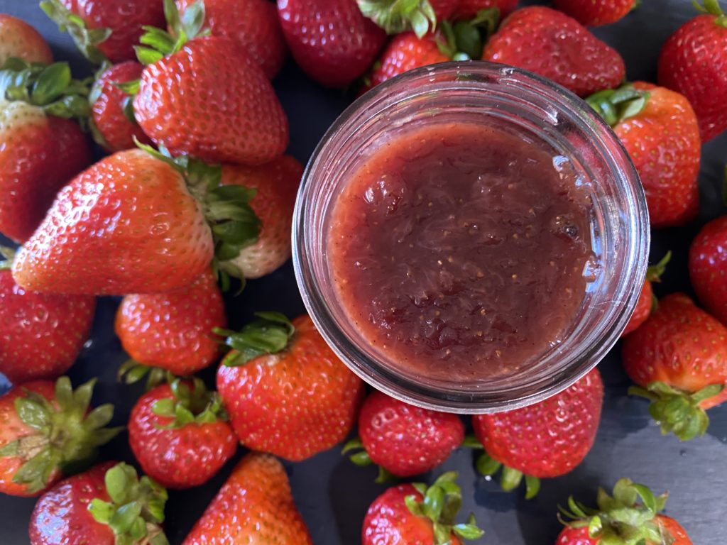 a jar of strawberry jam surrounded by beautiful fressh strawberries