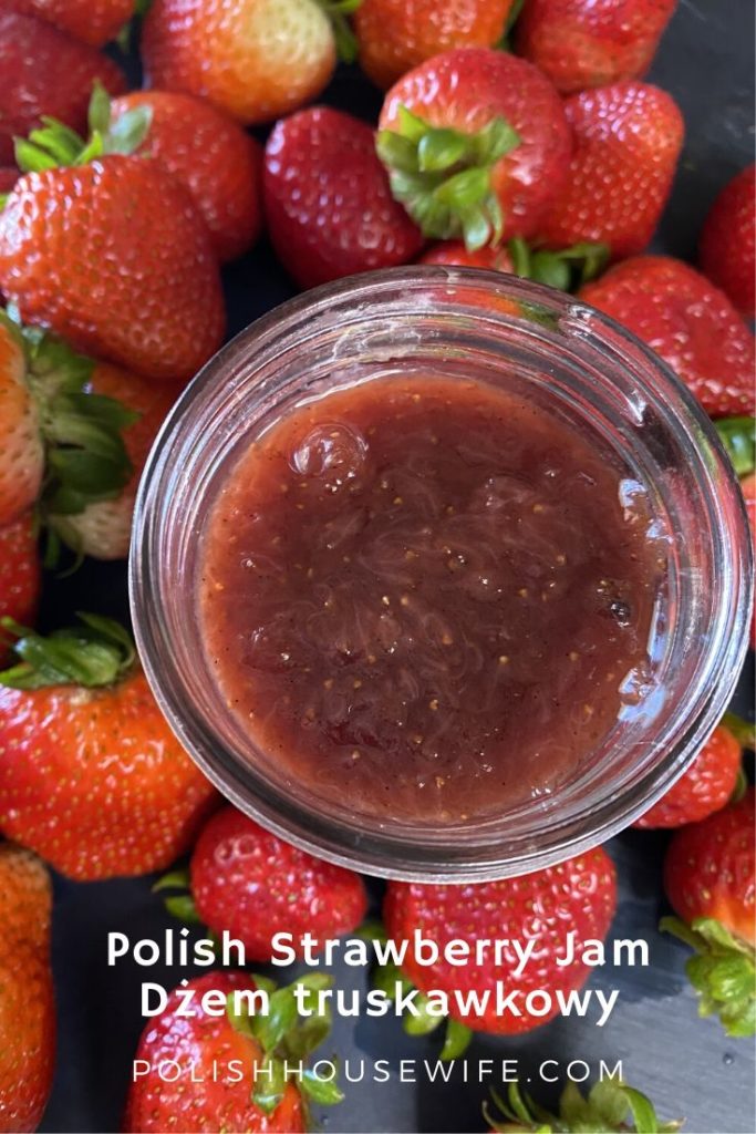 a jar of polish strawberry jam surrounded by fresh strawberries
