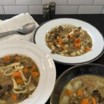 3 bowls of Polish mushroom soup on a dark countertop.